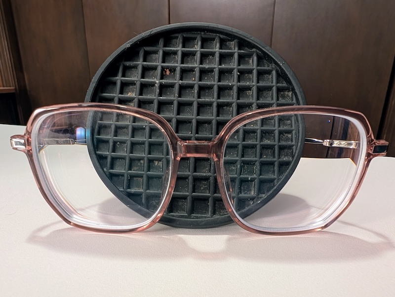 A pair of glasses with a coaster behind the eye pieces