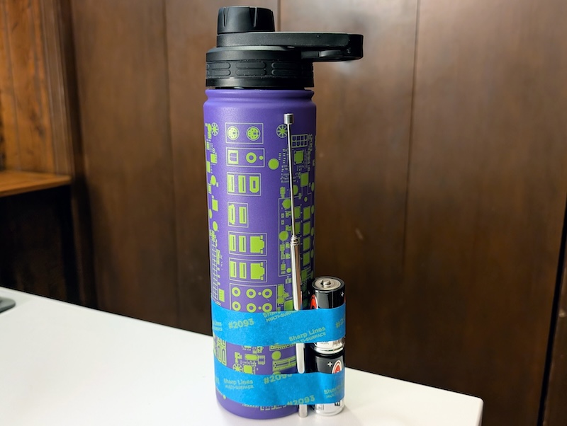 Two C-batteries taped to a water bottle with an antenna loosely attached.